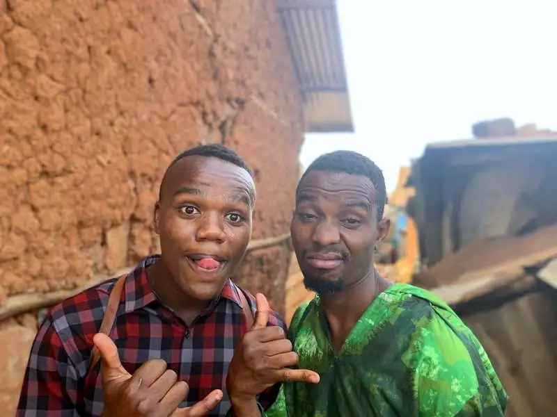 Two young men from Siaya County laughing with thumbs up