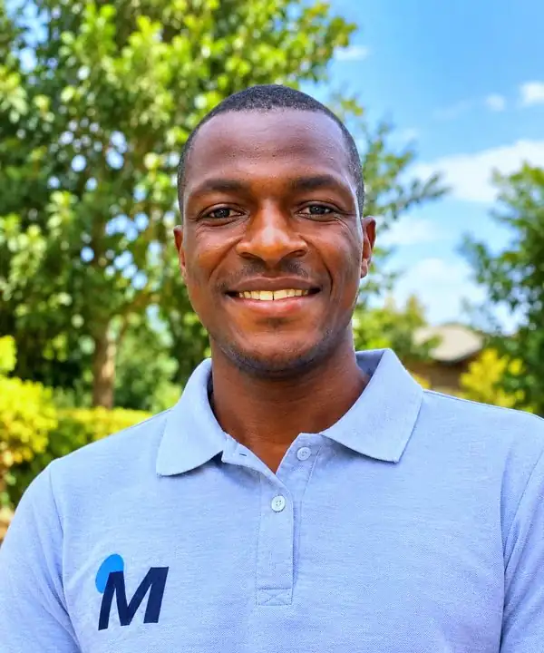A MOTHERLAND team member in a polo shirt with the M logo, smiling, Siaya County